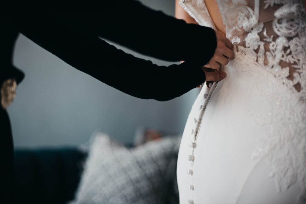 Bride getting fitted into a bridal gown by a bridal consultant